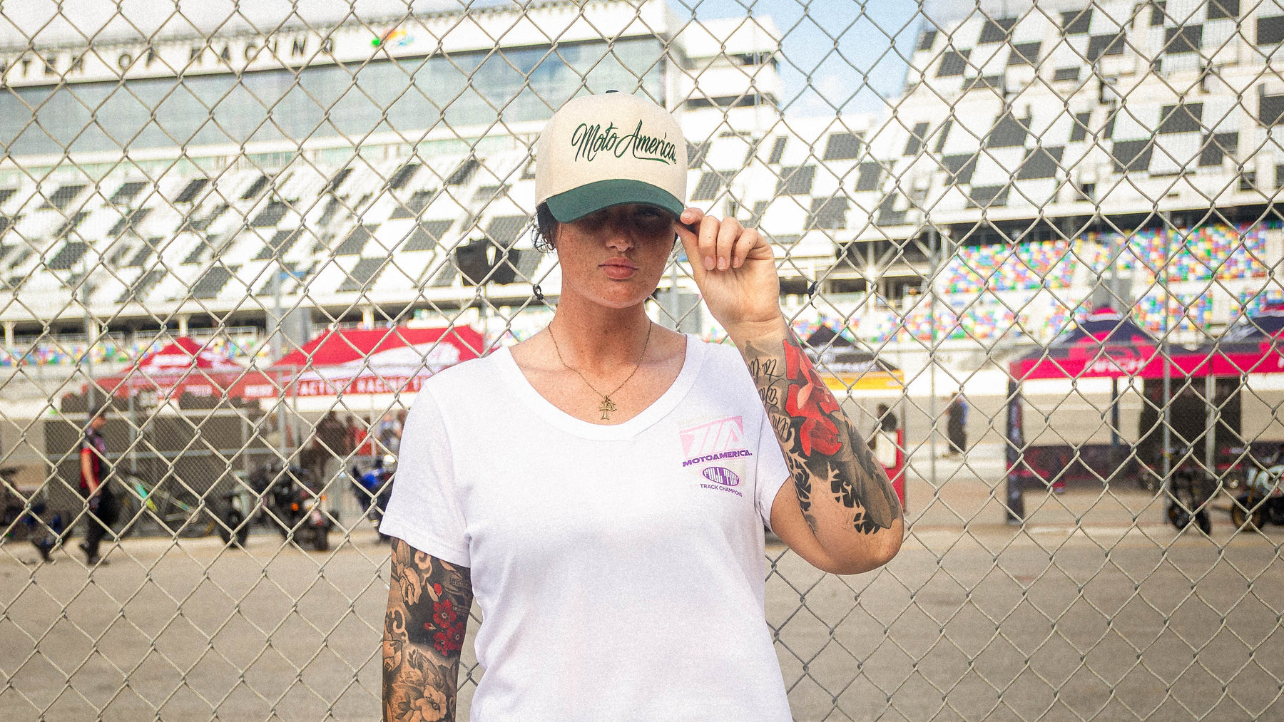 MotoAmerica cap and tee photographed at the racetrack fence
